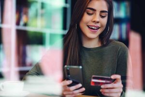 Woman using smartphone and a credit card for online shopping in